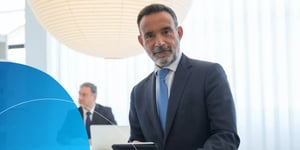 A man in a suit sitting in an office looking at the camera