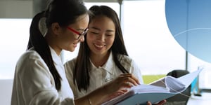 Two women looking at a book and smiling
