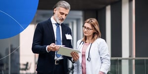 A sales rep explaining  a new drug research with his Ipad pro to woman doctor