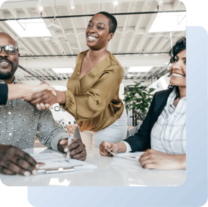 Frau in einem Führungkräftecoaching, beim Hände schütteln, sie lächelt. Die anderen Menschen lächeln auch 