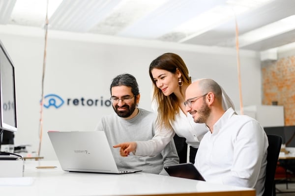 three employes looking into laptop screen and smiling