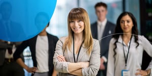 Woman standing in front of three people behind with arms crossed and smiling