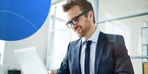 Man in suit smiling and looking at laptop