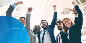five people with fists in the air cheering and smiling