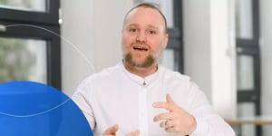 Man speaking into camera with open hand gesture
