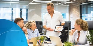 Four people in an office working together smiling