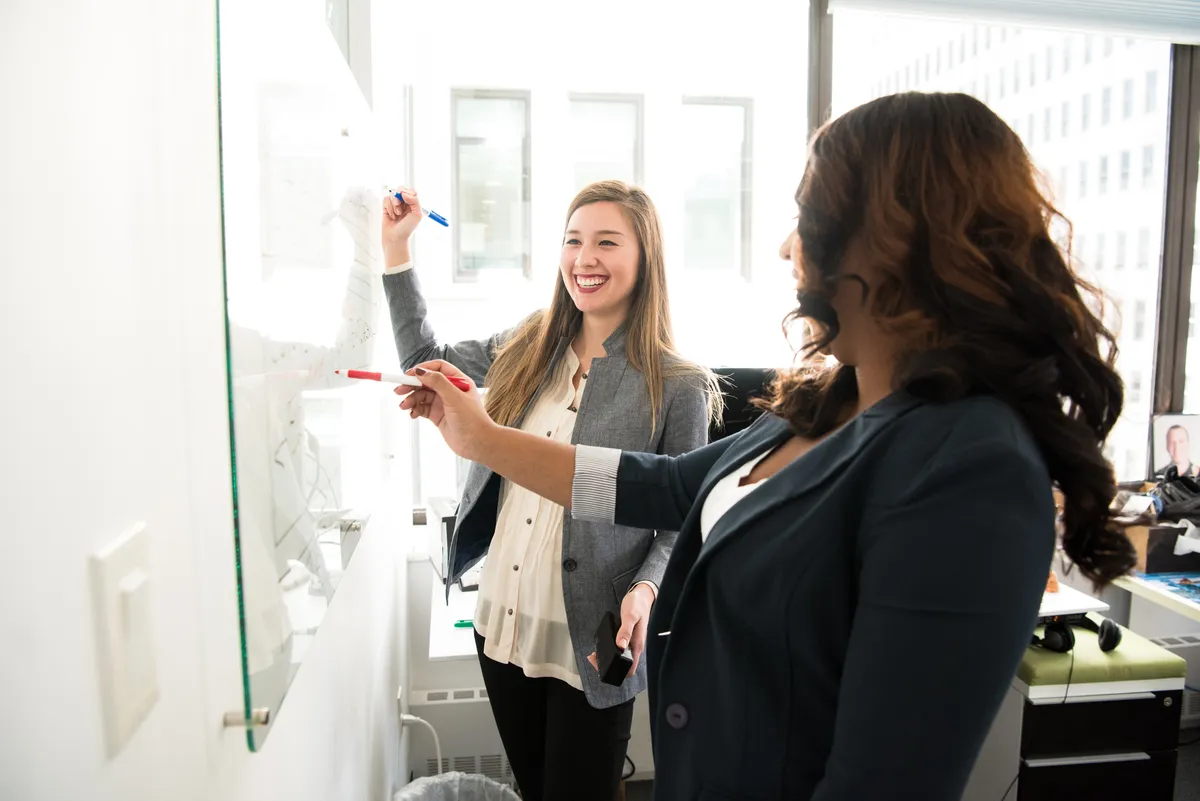 Two women brainstorming at a whiteboard